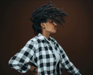 model in checked shirt tossing her dreadlocks